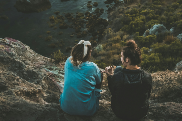 Twee vrouwen zitten te praten op een berg, dit symboliseert een ondernemer die verhalen vertelt tegen klanten en zo een vertrouwensband opbouwt.